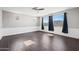 Open living room with stylish wood floors, paneled walls, and large windows with dark curtains at 16840 W Monroe St, Goodyear, AZ 85338