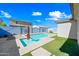 Backyard pool featuring bright blue water, artificial turf, an umbrella, and a clear blue sky at 16840 W Monroe St, Goodyear, AZ 85338