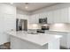 Spacious kitchen with an island featuring white cabinets, stainless appliances, and bright overhead lighting at 17836 W Mission Ln, Waddell, AZ 85355
