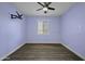 Light-filled bedroom boasts wood floors, a ceiling fan, blue walls and a large window at 20200 N Donithan Way, Maricopa, AZ 85138