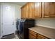 Laundry room boasts wooden cabinets, countertop space, and modern washer and dryer at 2038 W Whisper Rock Trl, Phoenix, AZ 85085