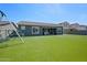 Wide view of the backyard featuring artificial turf, a play set, and covered patio at 22728 E Camacho Rd, Queen Creek, AZ 85142