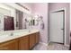 Bright bathroom with double sinks, neutral-colored cabinets, tiled floors, and a large mirror at 2721 E Schiliro Cir, Phoenix, AZ 85032
