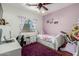 This bedroom features a white bedframe with a pink wall, a desk, and a fluffy purple rug at 2721 E Schiliro Cir, Phoenix, AZ 85032