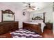 Cozy bedroom with classic furnishings, hardwood floors, and a comfortable bed topped with soft linens and a decorative ceiling fan at 2721 E Schiliro Cir, Phoenix, AZ 85032