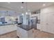 Spacious kitchen featuring stainless steel refrigerator, white cabinets, granite countertops, and eat-in island at 3901 E Packard Dr, Gilbert, AZ 85298