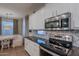 Eat-in kitchen boasts stainless appliances, white cabinets with granite countertops, and a cozy adjacent seating area at 3901 E Packard Dr, Gilbert, AZ 85298