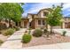 Inviting two-story home with a stone facade, a covered porch, and lush, low-water landscaping at 42711 N 45Th Dr, Phoenix, AZ 85087