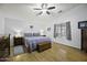 Spacious main bedroom with wood floors, ceiling fan, and chest at the foot of the bed at 42760 W Magnolia Rd, Maricopa, AZ 85138