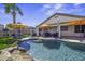 Relaxing pool view with clear blue water, rock waterfall, palm tree, and shaded lounge area at 42760 W Magnolia Rd, Maricopa, AZ 85138