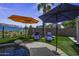 Poolside view of patio umbrellas, lounge chairs, and lush artificial turf at 42760 W Magnolia Rd, Maricopa, AZ 85138