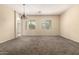 Spacious carpeted living room with neutral walls, large windows, and an elegant chandelier at 4335 E Sleighbell Dr, Gilbert, AZ 85297