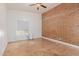 Bright bedroom with a brick accent wall, tile flooring, and a window providing natural light at 4401 E Hubbell St # 57, Phoenix, AZ 85008
