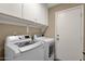 Modern laundry room with side-by-side washer and dryer with overhead cabinet storage at 4434 E Thistle Landing Dr, Phoenix, AZ 85044