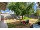 Lush backyard showcasing a mature tree and lawn equipment, all on a partially sunny day at 4513 W Yucca St, Glendale, AZ 85304