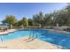Beautiful community swimming pool featuring lounge chairs and blue umbrellas for a resort style feel at 14870 W Encanto Blvd # 1106, Goodyear, AZ 85395