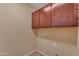 Laundry room with wood cabinets, ceramic flooring, and convenient utility connections at 16040 W Grant St, Goodyear, AZ 85338