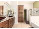 Bathroom featuring double sinks, granite countertop, wooden cabinets and a separate tub and shower at 16817 W Bradford Way, Surprise, AZ 85374