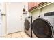 Well-lit laundry room featuring a modern washer and dryer set, storage cabinets, and convenient access to an exterior door at 16817 W Bradford Way, Surprise, AZ 85374