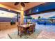 A covered outdoor dining area features a wooden table, chairs, and an outdoor grill with views of the pool and landscaped backyard at 2024 E Cherry Hills Pl, Chandler, AZ 85249