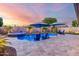 Inviting backyard with a swimming pool, spa, manicured landscaping, and comfortable seating under the beautiful evening sky at 2024 E Cherry Hills Pl, Chandler, AZ 85249