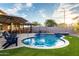 Serene pool area with outdoor kitchen, covered patio, lounge chairs, and artificial grass at 2024 E Cherry Hills Pl, Chandler, AZ 85249