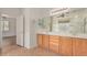 Bathroom with double sinks, wood cabinets, and a soaking tub next to the glass block window at 2112 E Yellowstone Pl Pl, Chandler, AZ 85249