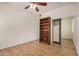 A well-lit bedroom with wood floors, a ceiling fan, an open bookcase and mirrored closet doors at 2112 E Yellowstone Pl Pl, Chandler, AZ 85249