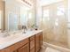 Well-lit bathroom features double sinks, neutral toned tile and a glass enclosed walk-in shower at 21134 W Green St, Buckeye, AZ 85396