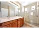 Bathroom with a double sink vanity and glass enclosed shower with tiled surround and shower bench at 21134 W Green St, Buckeye, AZ 85396