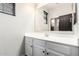 A well-lit bathroom featuring a large mirror, white cabinets, and a modern faucet at 21972 N 97Th Gln, Peoria, AZ 85383
