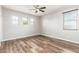 An airy bedroom featuring multiple windows, wood-look flooring, and a modern ceiling fan at 21972 N 97Th Gln, Peoria, AZ 85383