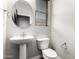 Modern powder room featuring a pedestal sink, round mirror, and neutral decor at 21972 N 97Th Gln, Peoria, AZ 85383