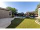 This beautiful backyard is landscaped with lush greenery, a pool and lounge chairs at 22290 E Escalante Rd, Queen Creek, AZ 85142