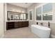 Modern bathroom featuring a soaking tub, vanity with cabinets, and a large mirror, creating a spa-like atmosphere at 22290 E Escalante Rd, Queen Creek, AZ 85142