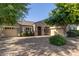 Paver driveway leads to a charming home with stone accents and lush, mature landscaping at 22290 E Escalante Rd, Queen Creek, AZ 85142