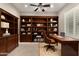 Elegant home office featuring custom built-in bookshelves, a large wooden desk, and a comfortable leather chair at 22290 E Escalante Rd, Queen Creek, AZ 85142