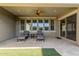 Covered patio with stone flooring, ceiling fan, and lounge chairs overlooking the yard at 22290 E Escalante Rd, Queen Creek, AZ 85142