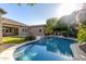 Sparkling backyard pool surrounded by lush, mature landscaping and a green yard at 22290 E Escalante Rd, Queen Creek, AZ 85142