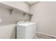 This laundry room features a new, white, stacked washer and dryer set and overhead shelving at 23195 S 226Th Way, Queen Creek, AZ 85142