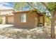 Tan single-story home shows a front entrance with desert landscaping and shade from a mature tree at 2327 E Meadow Land Dr, San Tan Valley, AZ 85140