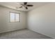 This bedroom features neutral carpet, a ceiling fan, and a window that lets in ample light at 2408 W Saint Kateri Dr, Phoenix, AZ 85041