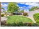 Lush backyard featuring a well-maintained lawn, mature trees, vibrant flowerbeds, and a privacy wall at 2920 W Michigan Ave, Phoenix, AZ 85053