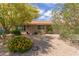 Single-story home with neutral tones and lush landscaping, including colorful flowers and mature trees at 2920 W Michigan Ave, Phoenix, AZ 85053