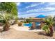 Inviting pool area with lounge chairs, desert landscaping, and a blue umbrella, creating a serene outdoor space at 2920 W Michigan Ave, Phoenix, AZ 85053