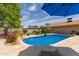 Refreshing pool area with lush landscaping, stone accents, and a relaxing lounge space under a blue umbrella at 2920 W Michigan Ave, Phoenix, AZ 85053