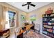 Home office space featuring a long desk, ceiling fan and backyard views through a window at 29749 N 130Th Dr, Peoria, AZ 85383