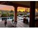 Inviting covered patio features comfortable seating, a dining table, and a stunning sunset view over the pool at 29749 N 130Th Dr, Peoria, AZ 85383