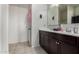 Well-lit bathroom with a double sink vanity, tile flooring, and a walk-in closet at 29809 W Columbus Ave, Buckeye, AZ 85396