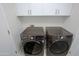 Well-lit laundry room has front loading washer/dryer with white cabinets above at 32472 N 68Th Pl, Scottsdale, AZ 85266